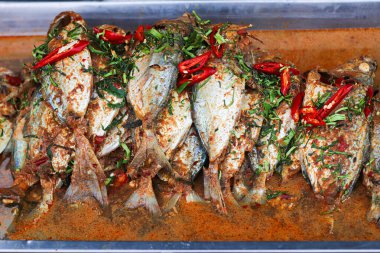 Lezzetli Tayland Chu Chee Uskumrusu, aromatik kırmızı köri ile pişirilmiş ve üzeri kaffir limon yaprağı ve kırmızı biberle kaplı. Tayland mutfağını temsil eden renkli, otantik bir sokak yemeği..