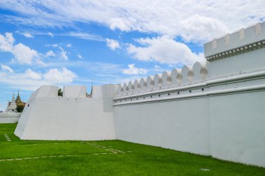 Wat Phra Kaews 'in Bangkok' taki Büyük Saray 'daki beyaz duvarı. Bulutlu açık mavi gökyüzü ve yemyeşil çimenler. Tarihi Tayland simgesi ve kültür mirası hedefi.