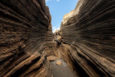 Güneş ışığı, tortul kaya katmanlarından oyulmuş dar bir kanyonun duvarlarını aydınlatıyor. Peyzaj ve doğa kavramı