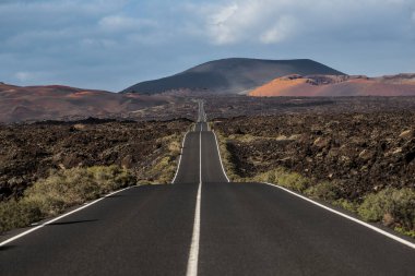 Lanzarote, kanarya adalarında volkanik bir araziyi geçen uzun asfalt yol. Peyzaj ve doğa kavramı
