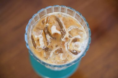 Sütlü ferahlatıcı buzlu kahvenin tepeden tırnağa görüntüsü. Krema ve dondurma sergileniyor. İçki, ahşap bir masanın üzerinde yeşil bir bardak üzerinde, kaburgalı bir bardakta servis edilir..