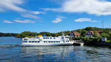 Stockholm, İsveç, 08.13.2025. İsveç 'te çift katlı bir turist teknesi. Yazın Stockholm etrafında dalgalanan adalar, mavi sularda yüzen bir tekne ve beyaz bulutlu mavi bir gökyüzü..