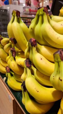 ripe yellow bananas in bunches on a market shelf, fruit display in a store, proper nutrition fruits