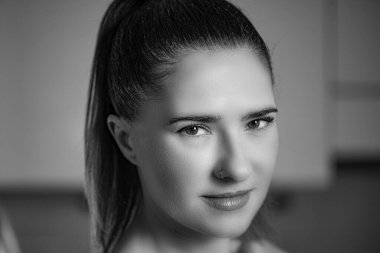 Çarpıcı özellikleri olan bir kadın düşünceli bir şekilde mesafeye bakar. Koyu renk saçları arkaya bağlanmış ve derin düşüncelere daldığı için ince bir burun halkası takıyor. Siyah beyaz fotoğraf..