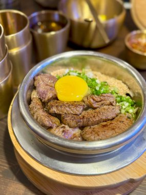 Sıcak taş kapta çiğ yumurta ve Kore sığır eti kasesi.