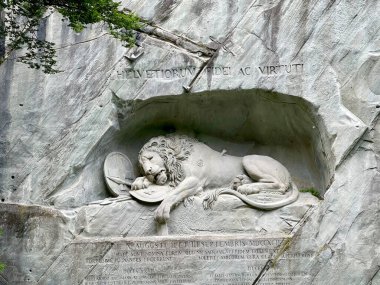 İsviçre 'nin Lucerne şehrinde bir kaya duvarına oyulmuş Aslan Anıtı' nın (Lwendenkmal) geniş görünümü, Fransız Devrimi sırasında ölen İsviçreli muhafızların anısına kalkanın üzerinde yatan ölen bir aslanı resmediyor..