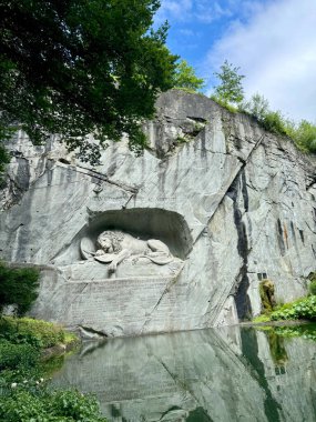İsviçre 'nin başkenti Lucerne' de, yeşil ve mavi gökyüzü ile çevrili ve Fransız Devrimi sırasında ölen İsviçreli muhafızların anısına bir kaya duvarına oyulmuş Aslan Anıtı 'nın (Lwendenkmal) geniş görünümü.