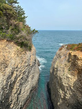Sütun bazalt tarafından oluşturulan dikey uçurumların çarpıcı bir görüntüsü, Nanatsugama kıyı şeridindeki turkuaz suyla dar bir deniz girişi ile ayrılmış..