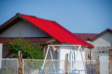 Kırmızı çatılı ve mavi gökyüzü olan bir kulübe.