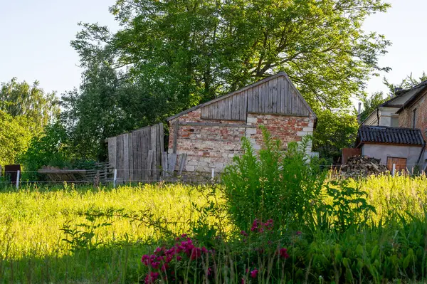 Ön planda bitkiler olan terk edilmiş eski bir ev.