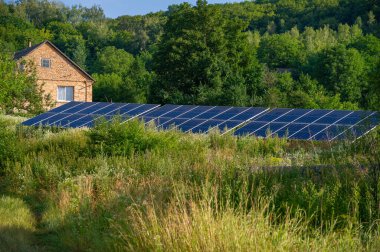 Evin yakınındaki yeşil çimlerin üzerindeki güneş panelleri
