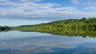 Suya yansıyan göl ve dağ manzarası ve gölde yüzen üç kaz.
