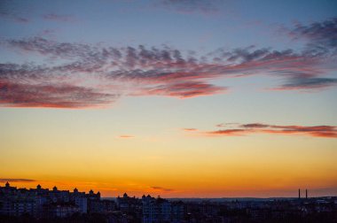 Şehrin üzerinde pembe bulutlarla gün batımı