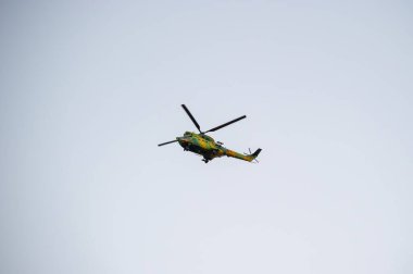 Kamuflaj boyalı bir helikopter, hareket halindeki pervaneleriyle gökyüzünde süzülüyor..