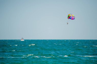  Bulgaristan 'da açık ve güneşli bir günde, canlı renkli bir paraşütün altında turkuaz okyanus dalgaları üzerinde süzülüyor