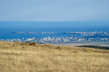 Bir Nesebar şehri, açık mavi gökyüzünün altında, geniş, kuru bir otlağın ötesine uzanır..