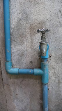 Mavi PVC Su Boruları ve Beton Duvardaki Eski Musluk