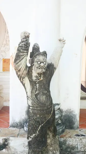 Tayland tapınağındaki Çinli bir muhafızın yıpranmış taş heykeli.