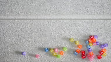 Beyaz bir yüzeye dağılmış çok renkli boncuklar.