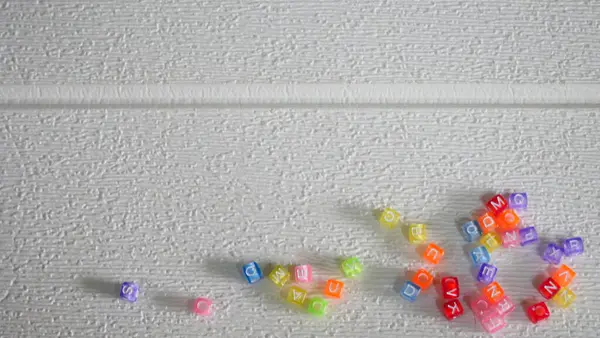 Beyaz bir yüzeye dağılmış çok renkli boncuklar.