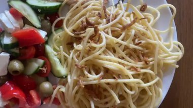 Pasta with a slice of fried turkey and a salad made from tomatoes, cucumber, red pepper, feta, and olives