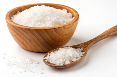 Beyaz arka planda deniz tuzu ve kaşık olan kase.