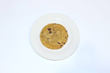 Temiz beyaz bir tabakta servis edilen taze pişmiş çikolatalı kurabiye leziz bir kombinasyon sunar: doku, aroma ve tatlı ya da atıştırmalık sunar..