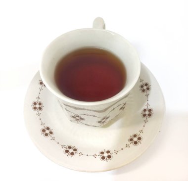 Eşleşen çay tabağında siyah çay ile doldurulmuş, beyaz arka planda izole edilmiş klasik çiçek çayı.