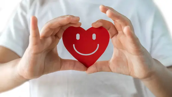 İnsan eli kırmızı kalp gülümseyen kağıt kesiği, sağlık ve sağlık, aşk, mutluluk, rahatlama, pozitif, dünya kalbi günü, iyi, sağlıklı, aile, sağlık, CSR, sigorta ve hastane konsepti