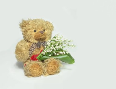           Boynunda sarı bir fiyonk ve bir buket çiçekle bir oyuncak ayı.                     