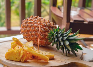         Dilimlenmiş ananas dilimli büyük olgun ananas, ahşap bir yemek tahtasının üzerinde, yakın plan..             