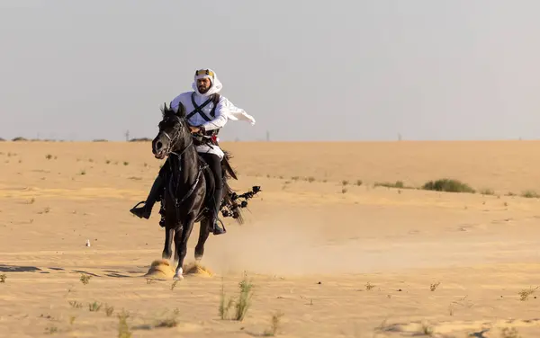 サウジアラビアの男性は砂漠で黒いスタリオンに乗っています — ストック写真