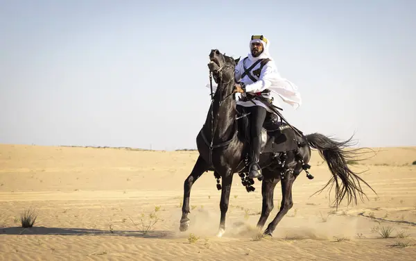 沙乌地阿拉伯人骑着他的黑马在沙漠中 — 图库照片