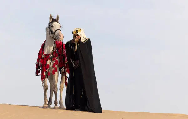 Саудовский Мужчина Традиционной Одежде Своим Белым Жеребцом Пустыне Нацеленным Винтовку — стоковое фото