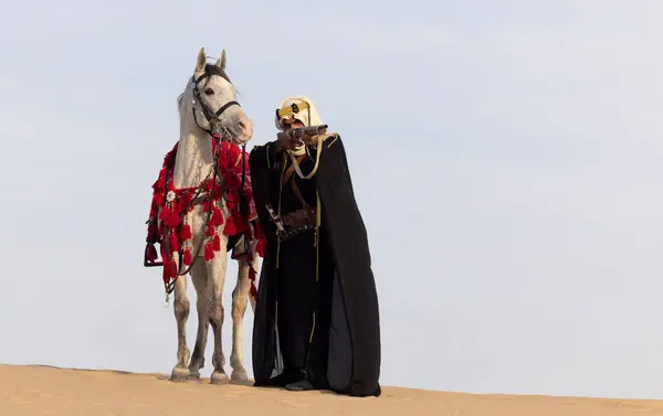 Suudi Adam Geleneksel Kıyafetleriyle Çölde Beyaz Aygırıyla Tüfeğini Doğrultuyor — Stok fotoğraf