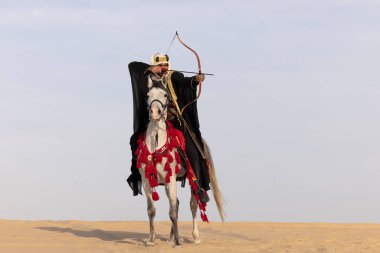 Beyaz aygırıyla geleneksel giyinmiş Suudi bir adam.
