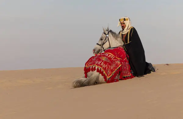 Saudischer Mann Traditioneller Kleidung Mit Seinem Weißen Hengst lizenzfreie Stockbilder
