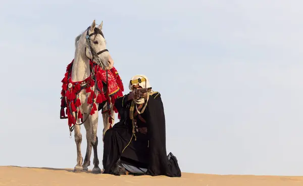 Саудовский Мужчина Традиционной Одежде Своим Белым Жеребцом Пустыне Нацеленным Винтовку Лицензионные Стоковые Фото