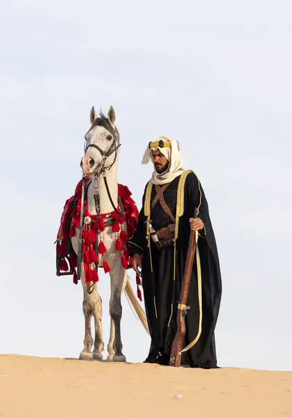 Saudischer Mann Traditioneller Kleidung Mit Seinem Weißen Hengst lizenzfreie Stockbilder