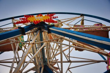 Mavi gökyüzüne karşı eski, paslı, paslı bir dönme dolaba yaklaş. Terk edilmiş dönme dolabın ayrıntılı görüntüsü.
