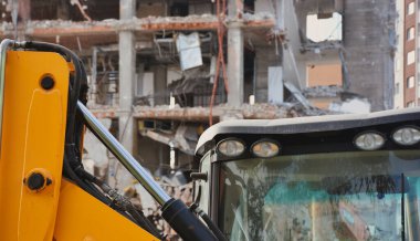 Arka planda gökdelenler olan bir yıkım alanında kazıcılar. Yeni mimariye yer açmak için eski bina yıkılıyor. İnşaat Yıkım Alanı