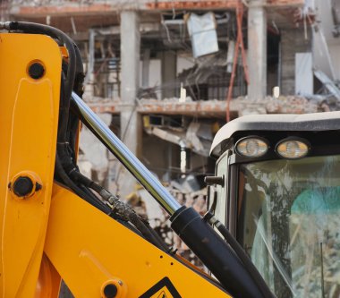 Arka planda gökdelenler olan bir yıkım alanında kazıcılar. Yeni mimariye yer açmak için eski bina yıkılıyor. İnşaat Yıkım Alanı