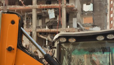 Arka planda gökdelenler olan bir yıkım alanında kazıcılar. Yeni mimariye yer açmak için eski bina yıkılıyor. İnşaat Yıkım Alanı