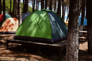 Ormanın kamp tarafındaki ahşap zemine kurulmuş bir kamp çadırı..