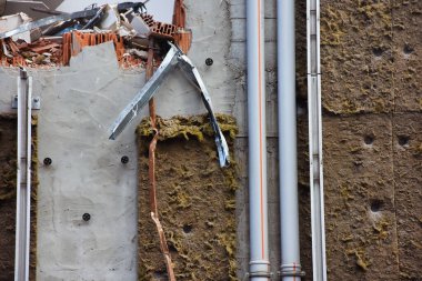  Çökmüş bir binanın duvar yüzeyinde izolasyon malzemesi ve plastik borular kullanılmış. İnşaat Yıkım Alanı.