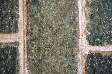 Arka plan olarak birkaç sıra sert desenli beton blok duvar, duvar kağıdı. Eski tarz tuğla ve birbirine geçmiş beton harç