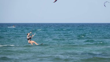 Profesyonel Uçurtma Sörfçüsü denizdeki dalgalar üzerinde hareket halinde. Uçurtma dalgalarda slalom yapıyor. Imbros Adası. Gökçeada, Çanakkale Türkiye 08.20.2022