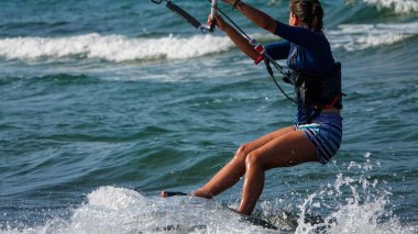 Profesyonel kadın uçurtma sörfçüsü denizdeki dalgalarda hareket halinde. Uçurtma dalgalarda slalom yapıyor. Imbros Adası. Gökçeada, Çanakkale Türkiye 08.20.2022