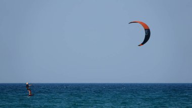 Profesyonel Uçurtma Sörfçüsü denizdeki dalgalar üzerinde hareket halinde. Uçurtma dalgalarda slalom yapıyor. Imbros Adası. Gökçeada, Çanakkale Türkiye 08.20.2022