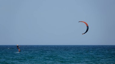 Profesyonel Uçurtma Sörfçüsü denizdeki dalgalar üzerinde hareket halinde. Uçurtma dalgalarda slalom yapıyor. Imbros Adası. Gökçeada, Çanakkale Türkiye 08.20.2022